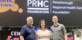 Flanked by Peterborough Century 21 Lakers board member Len Powers (left) and player Dylan Hutchison (right), Peterborough Regional Health Centre (PRHC) Foundation president and CEO Lesley Heighway dons a Peterborough Century 21 Lakers jersey at the Peterborough Memorial Centre on May 12, 2025 for an announcement of a partnership between the Lakers and the PRHC Foundation to support the $60 million Campaign for PRHC. (Photo courtesy of Peterborough Century 21 Lakers)