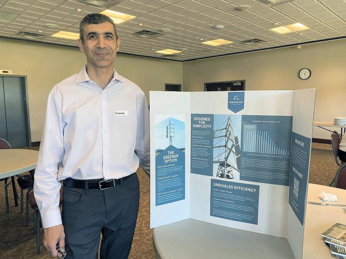 Eduard Yonathan of SanoStrategy Corporation with information about his company's wind turbine design, which is constructed out of sustainable materials and has a minimal environment footprint and wild-life friendly operation. (Photo courtesy of Rotary Club of Peterborough)