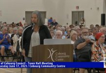 The crowd at a town hall meeting at Cobourg Community Centre on June 17, 2025 applauds a resident expressing concerns with the emergency homeless shelter at 310 Division St. in Cobourg. (kawarthaNOW screenshot of Town of Cobourg video)
