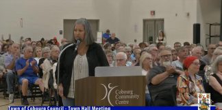 The crowd at a town hall meeting at Cobourg Community Centre on June 17, 2025 applauds a resident expressing concerns with the emergency homeless shelter at 310 Division St. in Cobourg. (kawarthaNOW screenshot of Town of Cobourg video)