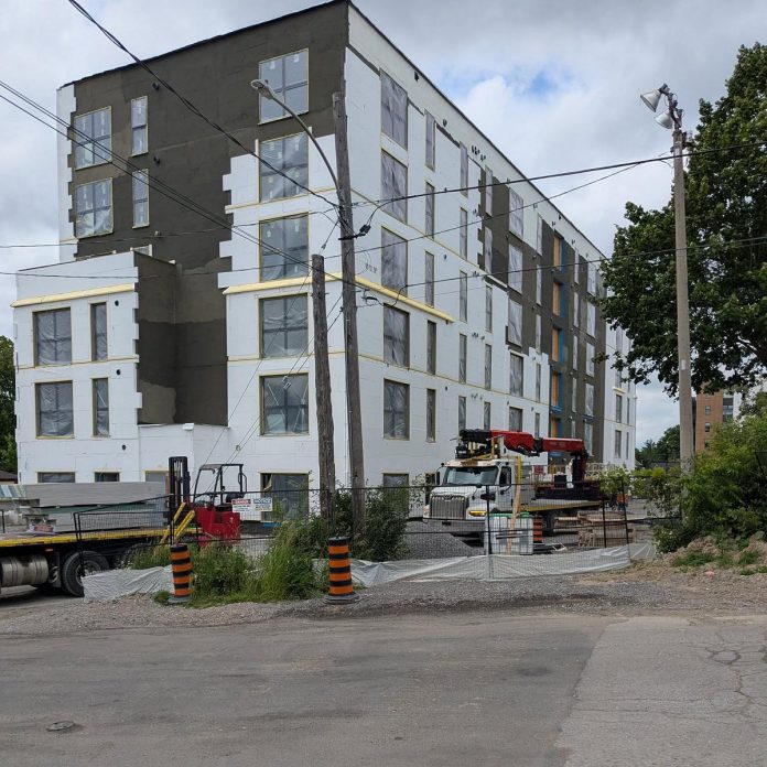 According to Paul Bennett, owner of Ashburnham Realty which is the developer of the six-storey building, the contractor was sanding the building's insulated concrete forms (ICF) on a windy day, allowing particles of polystyrene foam to blow off the construction site into the surrounding neighbourhood. A tarp has been placed around the bottom of the fence to try to prevent the particles from blowing off site. (Photo: Megan Boyles)