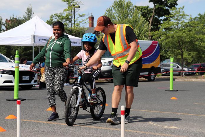 GreenUP cycling instructor Maxim Tandon helps a new rider with build confidence at a Let's Bike! pop-up in 2024. These free events offer bike check-ups, opportunity to practice cycling skills, and to try out a bike playground. The 2025 Let's Bike! events happen from 3:30 to 7 p.m. in Peterborough at the YMCA on June 17, and at the Asphodel-Norwood Community Centre in Norwood on June 25. (Photo: Jessica Todd / GreenUP)