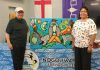 Former Nogojiwanong Friendship Centre board vice-president and president David Newhouse and Georgie Horton-Baptiste pictured in July 2024 with artwork by Indigenous artist Jared Tait. The non-profit organization in Peterborough is inviting community members to a gathering on June 20, 2025 to commemorate National Indigenous Peoples Day the following day. (Photo: Nogojiwanong Friendship Centre / Facebook)