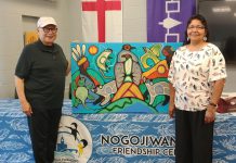 Former Nogojiwanong Friendship Centre board vice-president and president David Newhouse and Georgie Horton-Baptiste pictured in July 2024 with artwork by Indigenous artist Jared Tait. The non-profit organization in Peterborough is inviting community members to a gathering on June 20, 2025 to commemorate National Indigenous Peoples Day the following day. (Photo: Nogojiwanong Friendship Centre / Facebook)