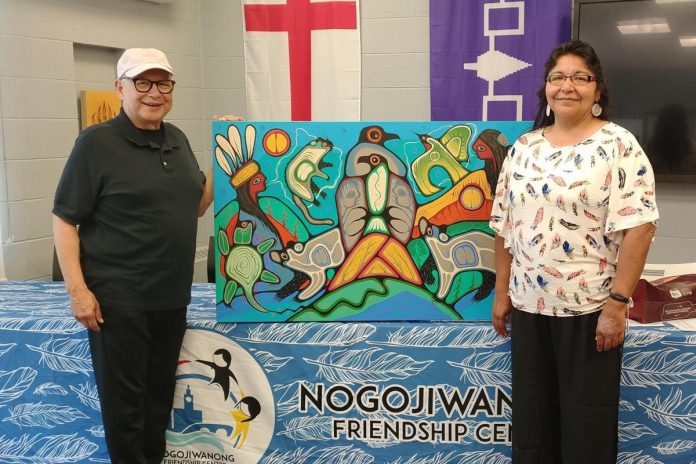 Former Nogojiwanong Friendship Centre board vice-president and president David Newhouse and Georgie Horton-Baptiste pictured in July 2024 with artwork by Indigenous artist Jared Tait. The non-profit organization in Peterborough is inviting community members to a gathering on June 20, 2025 to commemorate National Indigenous Peoples Day the following day. (Photo: Nogojiwanong Friendship Centre / Facebook) Former Nogojiwanong Friendship Centre board vice-president and president David Newhouse and Georgie Horton-Baptiste pictured in July 2024 with artwork by Indigenous artist Jared Tait. The non-profit organization in Peterborough is inviting community members to a gathering on June 20, 2025 to commemorate National Indigenous Peoples Day the following day. (Photo: Nogojiwanong Friendship Centre / Facebook)