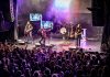 Retro rock tribute band Neon Nostalgic (Shawn Brady, Kevin Strom, Grant Strom, and John Johnstone) performs a free-admission concert in Del Crary Park on July 1, 2025 for the Canada Day edition of Peterborough Musicfest. The band performs hits from the 1980s and 1990s in synch with the artists' original music videos for the songs they perform. (Photo: Serrano Photography Studios)