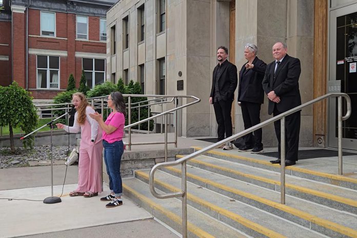 Sarah McNeilly, the sole director of Northcrest Neighbours for Fair Process (NNFP) Ltd., spoke to a crowd outside of Peterborough city hall on June 9, 2025 during the "Rally for Integrity" in support of councillors Alex Bierk and Joy Lachica (pictured with councillor Keith Riel), who the city's integrity commissioner found were intimidated and bullied by Mayor Jeff Leal. McNeilly spoke about NNFP's legal challenge against Leal's use of strong mayor powers to expedite the development of Brock Mission's proposed six-storey transitional housing building by exempting it from site plan requirements. (Photo: Jeannine Taylor / kawarthaNOW) Sarah McNeilly, the sole director of Northcrest Neighbours for Fair Process (NNFP) Ltd., spoke to a crowd outside of Peterborough city hall on June 9, 2025 during the "Rally for Integrity" in support of councillors Alex Bierk and Joy Lachica (pictured with councillor Keith Riel), who the city's integrity commissioner found were intimidated and bullied by Mayor Jeff Leal. McNeilly spoke about NNFP's legal challenge against Leal's use of strong mayor powers to expedite the development of Brock Mission's proposed six-storey transitional housing building by exempting it from site plan requirements. (Photo: Jeannine Taylor / kawarthaNOW)