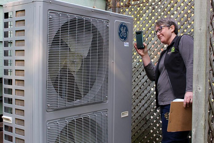 Better Homes Peterborough energy coach Clara Blakelock checks a heat pump nameplate at a client's home. She is available for consultations over the phone, in person, or at residences located in the City of Peterborough. (Photo: Yvonne Hollandy / GreenUP)