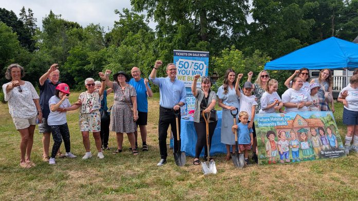 Attendees celebrate during a ground-breaking ceremony on July 9, 2025 for an accessible duplex to be built on Sophia Street in Peterborough East City for seven adult women with developmental disabilities. The project is a partnership between Habitat for Humanity Peterborough & Kawartha Region (Habitat PKR) and Our Daughters' Home, whose founder Jane Bischoff is pictured at the far left. (Photo: Bruce Head / kawarthaNOW)