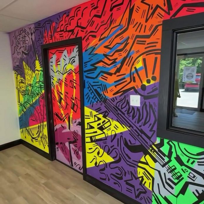 Peterborough illustrator and muralist Jason Wilkins has painted a mural for Michael Beauclerc's new Mad Music School in Juliann's Plaza at 3347 Lakefield Road in Lakefield. Wilkins and Beauclerc have been friends since high school. The completed mural will be unveiled during a family-friendly soft-opening celebration from 10 a.m. to noon on July 6, 2025 featuring live instructor demos, a tour of the studios, treats and refreshments from Stuff'd bakery, and raffle prizes donated by other local businesses. (kawarthaNOW screenshot of Jason Wilkins video)