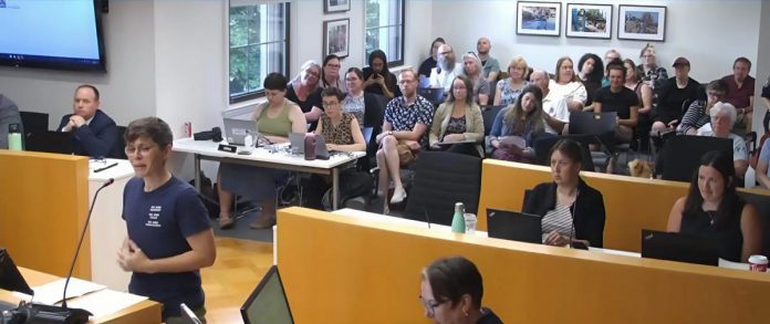Auden Palmer, director of outreach services at One City Peterborough, addresses Peterborough city council on July 2, 2025 before councillors voted 6-5 against providing continued funding for expanded services at Trinity Centre in 2026 for people experiencing homelessness. (kawarthaNOW screenshot of City of Peterborough video)