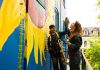 Zephyr Bugelli gives a high five to his sister Trinity as they restore the iconic sunflower mural at The Only Café in downtown Peterborough, which was originally painted by Jeremy Moore more than 25 years ago. Zephyr says it feels like a full-circle moment as the siblings' mother used to take them to The Only when they were children. (Photo: Zach Ward)