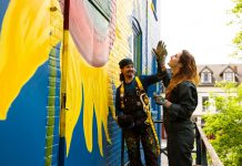 Zephyr Bugelli gives a high five to his sister Trinity as they restore the iconic sunflower mural at The Only Café in downtown Peterborough, which was originally painted by Jeremy Moore more than 25 years ago. Zephyr says it feels like a full-circle moment as the siblings' mother used to take them to The Only when they were children. (Photo: Zach Ward)
