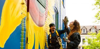Zephyr Bugelli gives a high five to his sister Trinity as they restore the iconic sunflower mural at The Only Café in downtown Peterborough, which was originally painted by Jeremy Moore more than 25 years ago. Zephyr says it feels like a full-circle moment as the siblings' mother used to take them to The Only when they were children. (Photo: Zach Ward)