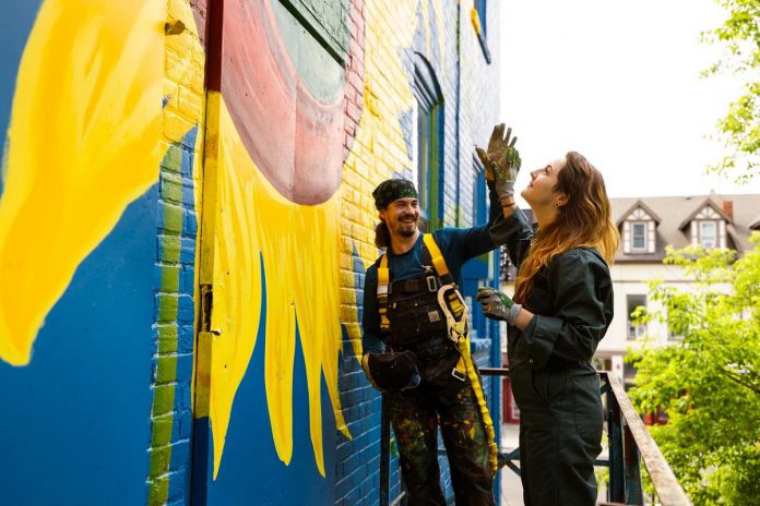 Zephyr Bugelli gives a high five to his sister Trinity as they restore the iconic sunflower mural at The Only Café in downtown Peterborough, which was originally painted by Jeremy Moore more than 25 years ago. Zephyr says it feels like a full-circle moment as the siblings' mother used to take them to The Only when they were children. (Photo: Zach Ward)