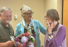 Incoming Northumberland Hills Hospital (NHH) Auxiliary president Rick Riley and Jennifer Gillard, NHH's vice-president of patient experience, public affairs, and strategic partnerships, present flowers to outgoing NHH Auxiliary president Selena Forsyth (right) at the auxiliary's annual meeting on July 24, 2025 at the Cobourg hospital. (Photo: NHH)