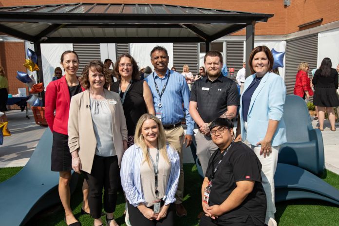 Representatives from Peterborough Regional Health Centre (PRHC) leadership and the hospital's mental health and addictions services team joined the PRHC Foundation and donors on August 6, 2025 to celebrate the opening of the donor-funded Psychiatric Intensive Care Unit (PICU) courtyard. Pictured from left to right are PRHC president of finance and corporate services and chief financial officer Jen Taylor, PRHC director of mental health and addictions Jennifer Cox, PRHC outpatient mental health manager Miriam McCann, PRHC RN Erica Earl (kneeling), PRHC mental health and addictions chief and medical director Dr. Raj Baskar, PRHC PICU manager Dakota Forsyth, PRHC RN Shayne Luangvisa (kneeling), and PRHC Foundation president and CEO Lesley Heighway. (Photo: Jordan Lyall Photography for kawarthaNOW)