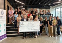 Kawartha Youth Orchestra volunteer John Good and board vice chair Joy Simmonds accept a $10,000 donation from 100 Women Peterborough founding member Wendy Hill as other members of the collective philanthropy group look on during the group's third meeting of 2025 in the lobby of the Venture North building on Tuesday, September 16. (Photo courtesy of 100 Women Peterborough)