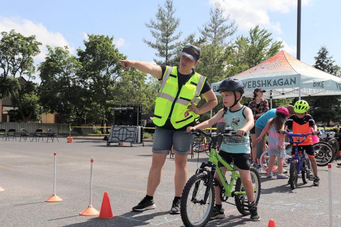 GreenUP director of programs Natalie Stephenson directs a participant at a community Let's Bike! cycling pop-up hosted at the Balsillie Family YMCA. Active School Travel Peterborough trains cycling educators and hosts events throughout the community to educate youth on bike skills and safety. (Photo: Jessica Todd / GreenUP)