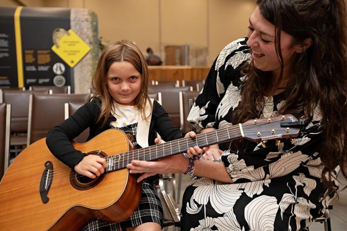 A young fan tries out Terra Lightfoot's guitar during "Raise a Little Shell," a conservation awareness event held on September 4, 2025 in the education centre of the Ontario Turtle Conservation Centre's new facility on Television Road in Peterborough. (Photo: Jordan Lyall Photography for kawarthaNOW)