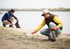 Two male volunteers collection trash on a beach. (Stock photo)