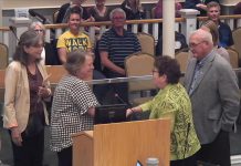 Catherine McNeely accepts the "Bee a Hero" award from City of Kawartha Lakes councillor Pat Warren as the city's environmental advisory committee Deb Pearson (left) and Mayor Doug Elmslie look on during the committee of the whole meeting on October 7, 2025. (kawarthaNOW screenshot of City of Kawartha Lakes video)