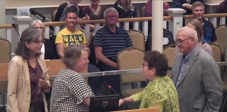 Catherine McNeely accepts the "Bee a Hero" award from City of Kawartha Lakes councillor Pat Warren as the city's environmental advisory committee Deb Pearson (left) and Mayor Doug Elmslie look on during the committee of the whole meeting on October 7, 2025. (kawarthaNOW screenshot of City of Kawartha Lakes video)