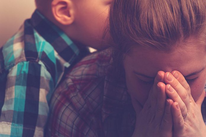 A women covers her face with her hands with a young boy in the background. (Stock photo) A women covers her face with her hands with a young boy in the background. (Stock photo)