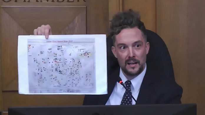 Peterborough city councillor Alex Bierk displays an "intake clinic hazard map," from a 2017 Unifor report detailing the toxic chemical exposures at the General Electric site between 1945 and 2000, during a general committee meeting on October 6, 2025 when council considered a notice of demolition of a large number of vacant buildings at the historic factory complex at 107 Park Street North. (kawarthaNOW screenshot of City of Peterborough video)