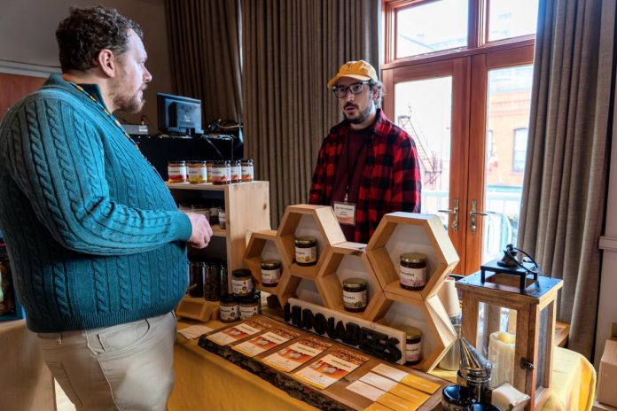 Dave Nicolaou (right), owner of Hunnabees Honey & Co. in Millbrook, was one of several local producers and makers who showcased and offered samples of their products at the "Taster's Market" during the inaugural Regional Tourism Summit hosted by the Regional Tourism Organization 8 (RTO8) at the Capitol Theatre in Port Hope on October 21, 2025. (Photo courtesy of RTO8)