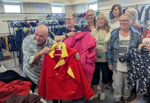 United Way Peterborough & District CEO Jim Russell and Bev Assinck of Peterborough Action for Tiny Homes (PATH) hold up clothing on October 8, 2025 during the launch of the annual Coats for Community campaign at PATH's location at 385 Lansdowne Street East in Peterborough. (Photo: United Way Peterborough & District)