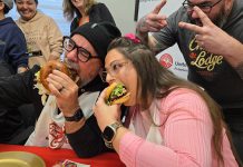 "Burger ambassadors" Jason Wilkins and Tiffany Arcari sink their teeth into burger creations from Double Dz's and Chemong Lodge (with Chemong Lodge's sous chef Sean Crooks giving the victory sign) during the launch of the United Way Peterborough & District's inaugural Ultimate Burger Battle community fundraiser on October 30, 2025 at the United Way office. During the month of November, eight participating restaurants will be creating a unique and creative burger in a friendly competition for the title of Ultimate Burger of the Year, with $2 from every burger sold being donated to the United Way. (Photo: Jeannine Taylor / kawarthaNOW)