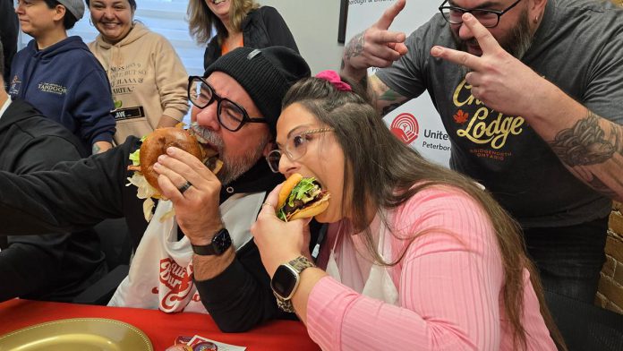 "Burger ambassadors" Jason Wilkins and Tiffany Arcari sink their teeth into burger creations from Double Dz's and Chemong Lodge (with Chemong Lodge's sous chef Sean Crooks giving the victory sign) during the launch of the United Way Peterborough & District's inaugural Ultimate Burger Battle community fundraiser on October 30, 2025 at the United Way office. During the month of November, eight participating restaurants will be creating a unique and creative burger in a friendly competition for the title of Ultimate Burger of the Year, with $2 from every burger sold being donated to the United Way. (Photo: Jeannine Taylor / kawarthaNOW) "Burger ambassadors" Jason Wilkins and Tiffany Arcari sink their teeth into burger creations from Double Dz's and Chemong Lodge (with Chemong Lodge's sous chef Sean Crooks giving the victory sign) during the launch of the United Way Peterborough & District's inaugural Ultimate Burger Battle community fundraiser on October 30, 2025 at the United Way office. During the month of November, eight participating restaurants will be creating a unique and creative burger in a friendly competition for the title of Ultimate Burger of the Year, with $2 from every burger sold being donated to the United Way. (Photo: Jeannine Taylor / kawarthaNOW)