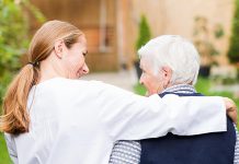 A young woman with her arm around the shoulders of an elderly person. (Stock photo)