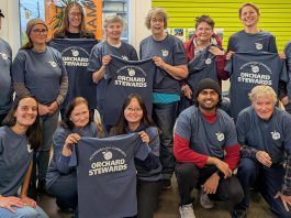 The Peterborough Community Orchard Stewards recently gathered at the GreenUP office for an end-of-season lunch. Pictured here taking a break from reflection and goal setting to show off their newly printed T-shirts, the group tends to 13 fruit orchards planted in neighbourhoods around Peterborough. (Photo: Tegan Moss / GreenUP)