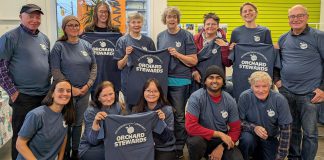 The Peterborough Community Orchard Stewards recently gathered at the GreenUP office for an end-of-season lunch. Pictured here taking a break from reflection and goal setting to show off their newly printed T-shirts, the group tends to 13 fruit orchards planted in neighbourhoods around Peterborough. (Photo: Tegan Moss / GreenUP)