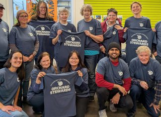 The Peterborough Community Orchard Stewards recently gathered at the GreenUP office for an end-of-season lunch. Pictured here taking a break from reflection and goal setting to show off their newly printed T-shirts, the group tends to 13 fruit orchards planted in neighbourhoods around Peterborough. (Photo: Tegan Moss / GreenUP)