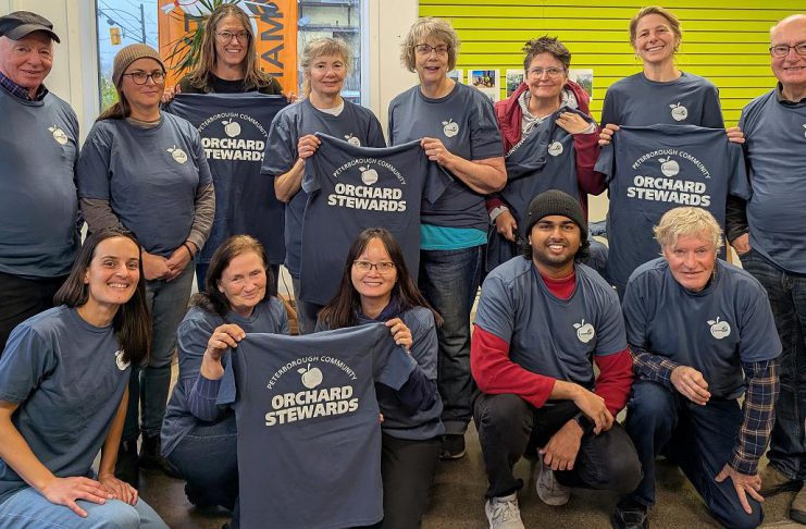 The Peterborough Community Orchard Stewards recently gathered at the GreenUP office for an end-of-season lunch. Pictured here taking a break from reflection and goal setting to show off their newly printed T-shirts, the group tends to 13 fruit orchards planted in neighbourhoods around Peterborough. (Photo: Tegan Moss / GreenUP)