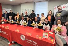 Representives from the eight restaurants in the city and county of Peterborough that are participating in the United Way Peterborough & District’s inaugural Ultimate Burger Battle stand behind the eight "burger ambassadors" during the October 30, 2025 launch of the community fundraiser. Paul Rellinger, Laura Montague, Dan O'Toole, Neil Morton, Nour Mazloum, Pete Dalliday, Jason Wilkins, and Tiffany Arcari) who will be promoting the November event. Along with awards for the Ultimate Burger of the Year and Most Burgers Sold, the fundraiser will include the People’s Choice Awards, whose winners will be selected by community members voting online for their favourite burger. (Photo: Jeannine Taylor / kawarthaNOW)