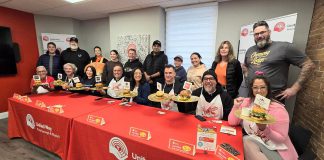 Representives from the eight restaurants in the city and county of Peterborough that are participating in the United Way Peterborough & District’s inaugural Ultimate Burger Battle stand behind the eight "burger ambassadors" during the October 30, 2025 launch of the community fundraiser. Paul Rellinger, Laura Montague, Dan O'Toole, Neil Morton, Nour Mazloum, Pete Dalliday, Jason Wilkins, and Tiffany Arcari) who will be promoting the November event. Along with awards for the Ultimate Burger of the Year and Most Burgers Sold, the fundraiser will include the People’s Choice Awards, whose winners will be selected by community members voting online for their favourite burger. (Photo: Jeannine Taylor / kawarthaNOW)