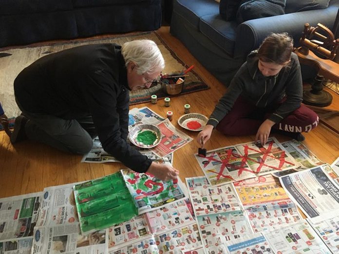 A fun way to personalize gift wrap is to decorate with paint or compostable elements from nature like dried oranges or pinecones. In this photo, gift givers are preparing newsprint with original artwork. (Photo: Jackie Donaldson / GreenUP)