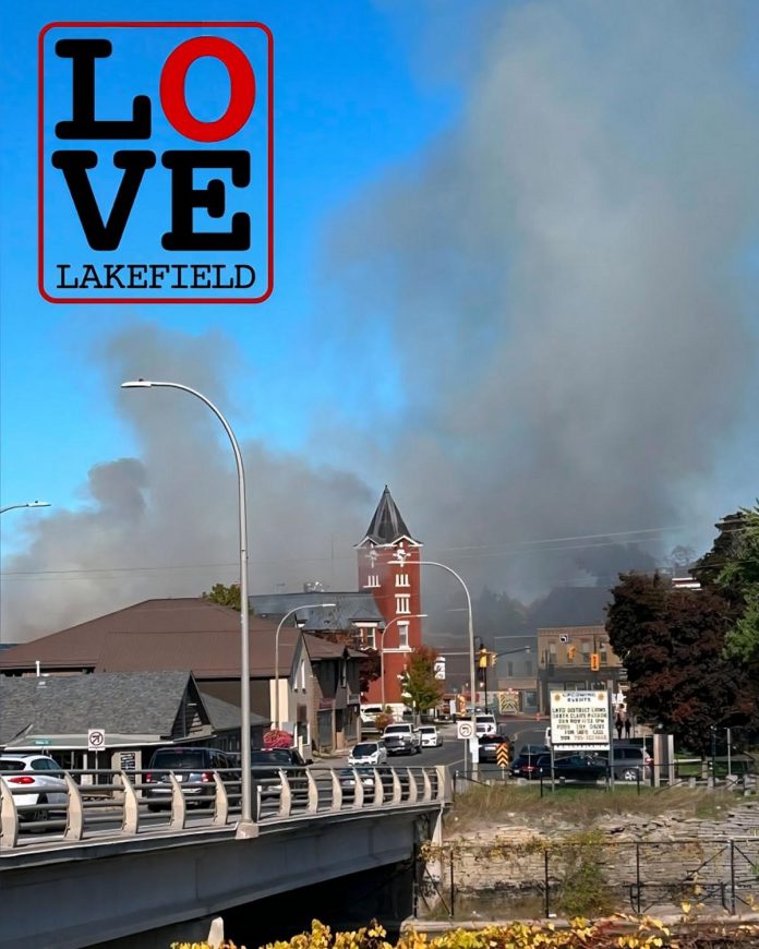 When a fire destroyed the Kawartha Home Hardware building, including the upper-level apartments, on October 9, 2025, Lakefield Youth Unlimited posted a photo on Facebook of the smoke billowing in downtown Lakefield from their location across the bridge and included the Love Lakefield logo, which was originally designed 10 years earlier. (Photo: Lakefield Youth Unlimited)