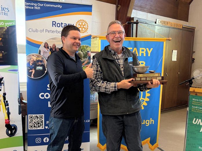 As Prince of Wales Elementary School Brad Conlin gives the thumbs up, Rotarian Nick Avlonitis accepts the Koeslag Cup on behalf of the Friday breakfast crew at the Rotary Club of Peterborough's annual Christmas lunch at Northminster United Church on December 22, 2025. Named after the late Peter Koeslag, a dedicated Prince of Wales breakfast club volunteer, the cup is awarded to the Rotary-led team that makes the most nutritious and delicious breakfast for the school's students. (Photo courtesy of Rotary Club of Peterborough)