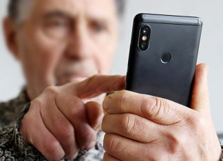 An elderly man using a cell phone. (Stock photo)