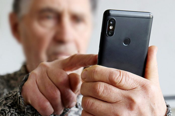 An elderly man using a cell phone. (Stock photo)