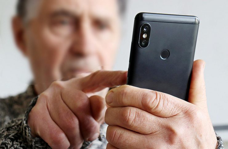 An elderly man using a cell phone. (Stock photo)