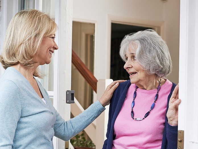 A woman checking on an elderly female neighbour. (Stock photo)