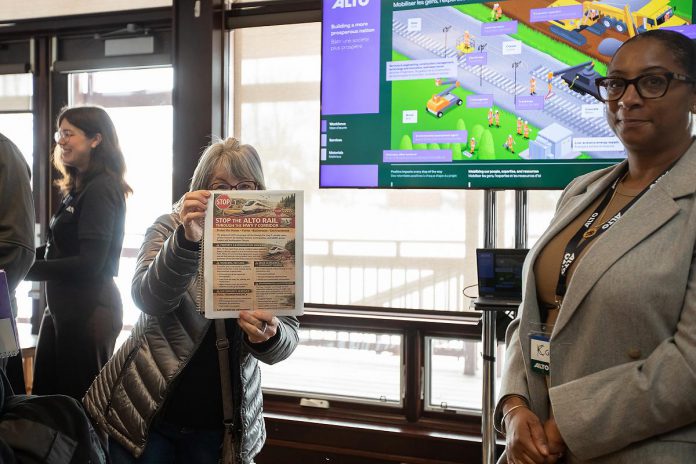 An attendee at the open house on the proposed Alto high-speed rail network between Toronto and Quebec City, held at the McDonnel Street Activity Centre in Peterborough on February 26, 2026, displays a flyer outlining concerns with the project, including property and expropriation concerns. (Photo: Jordan Lyall / kawarthaNOW)