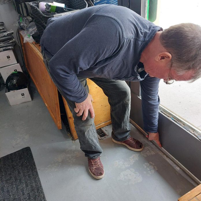 Vern Windrem of Green Street in downtown Peterborough checks for leaks after installing a new front door draft plate. From heat pumps and solar panels to weather stripping and equipment maintenance, energy efficiency for small business comes in all sizes. GreenUP and the Peterborough DBIA are inviting small business owners to a free breakfast open house on February 18, 2026, where energy experts will be available to answer questions. (Photo: Angella Windrem / Green Street)