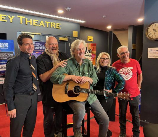 Joe Grant of LLF Lawyers, United Way Peterborough & District executive director Jim Russell, performer musician Mark Beatty, main stage emcee Ella Bates, and event co-founder and organizer Paul Rellinger during a media event at Showplace Performance Centre on February 12, 2026 to promote the Peterborough Performs VI: Musicians United To End Homelessness benefit concert on Thursday, February 26. (Photo: Adeline Murphy / United Way)